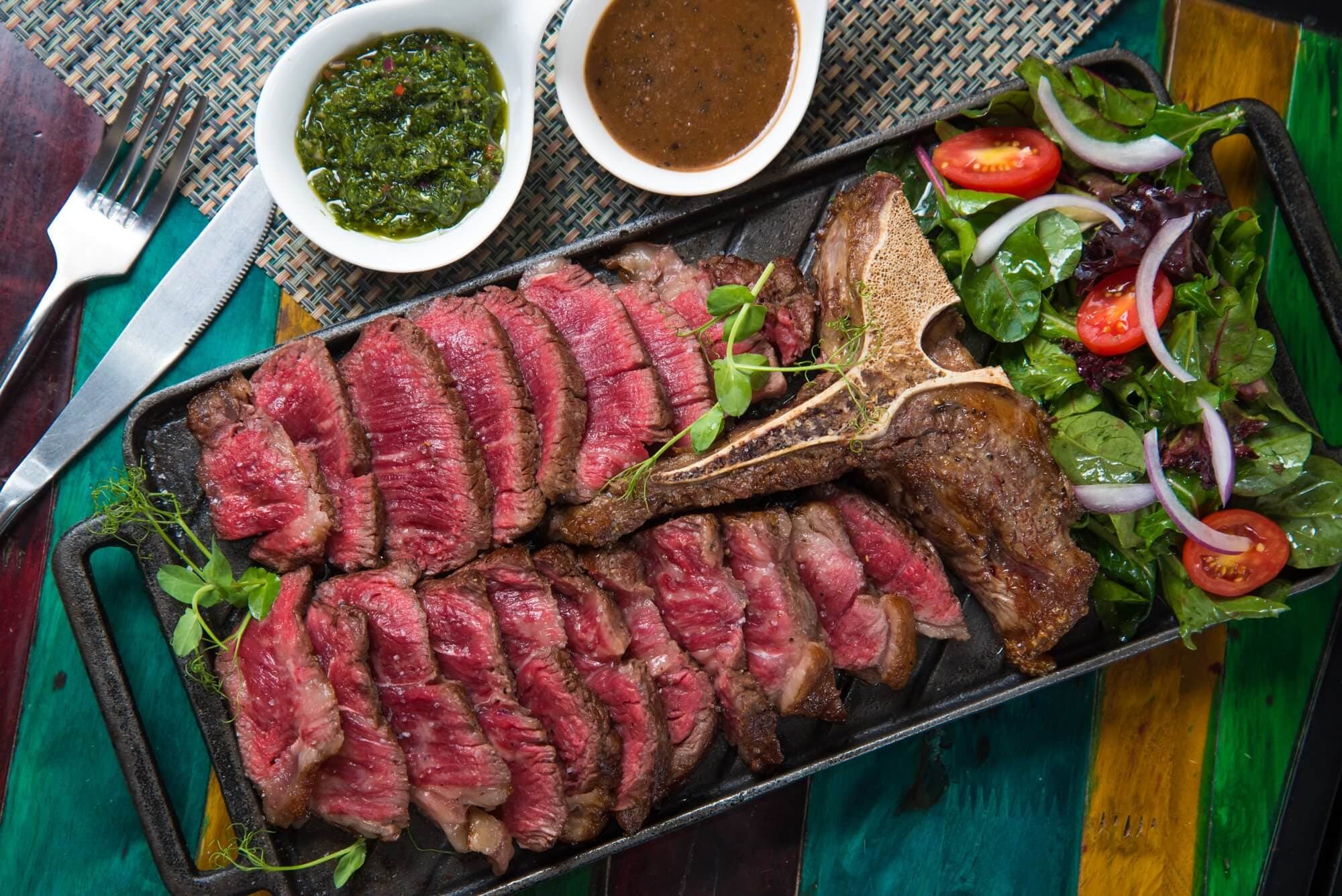 Sliced wagyu steak on cast iron with chimichurri